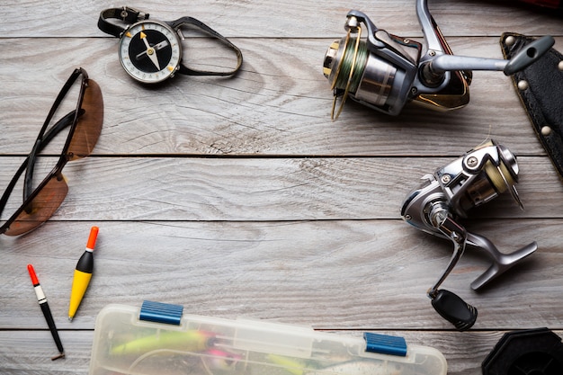 Frame met vissersdoos, spoelen, visboei, kompas, mes en glazen op houten achtergrond