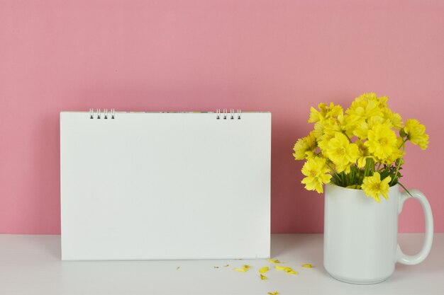 Frame mockup Blank calendar with yellow flowers in vase on pink