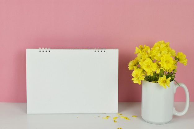 Frame mockup Lege kalender met gele bloemen in vaas op roze