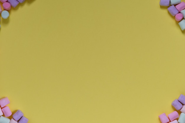 Foto cornice di caramelle gommosa e molle multicolori su sfondo giallo