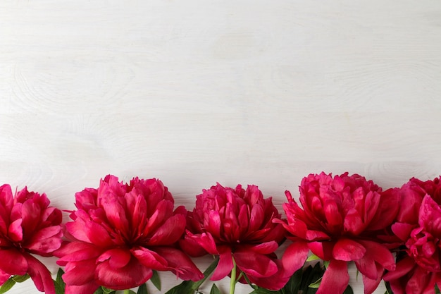 Фото Рамка из красивых ярко-розовых цветов пиона на белом фоне деревянных. вид сверху. место для текста