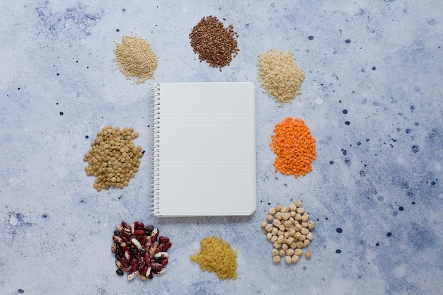 사진 파란색 배경에 곡물 시리얼 식품 씨앗 및 노트북의 프레임 텍스트 복사 공간이 있는 건강 식품 개념