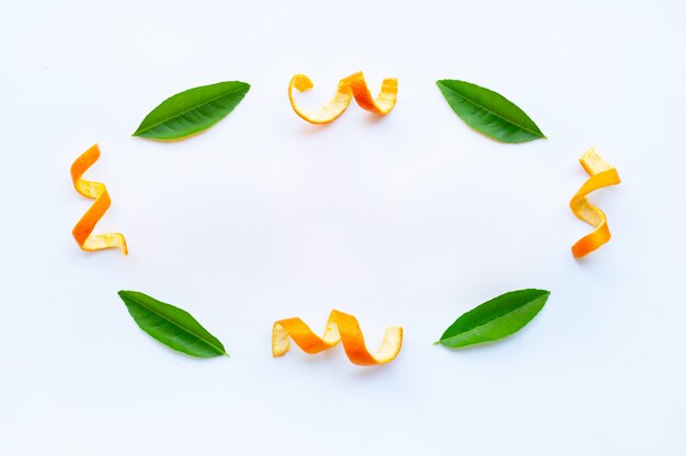 Frame of orange peels with green  leaves on white