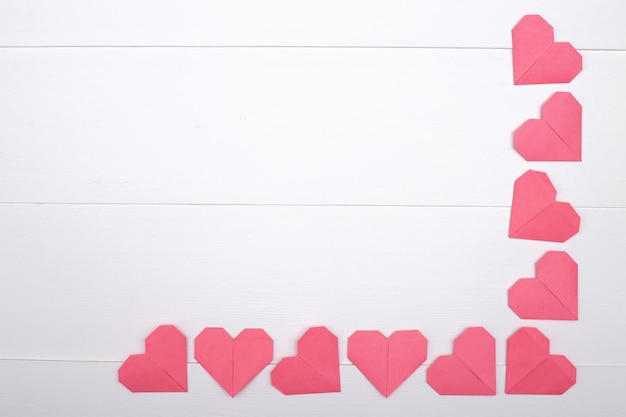 A frame of pink hearts on a white surface with space for copying