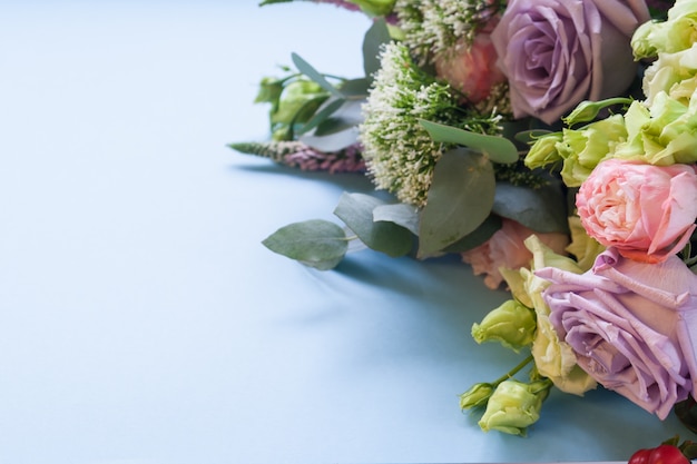 보라색과 분홍색 장미, 흰색 Lisianthus 및 파란색 배경에 다른 꽃의 프레임.