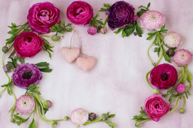 a frame of ranunculus and two pink hearts