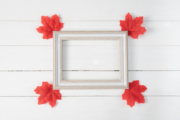 Frame and Red maple leaves on white wooden background. Autumn, fall , Top view, copy space.