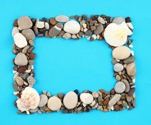 Photo frame of sea stones on color background