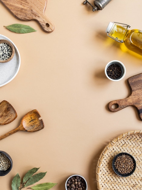 Frame of small bowls various dry spices, wood kitchen utensils, olive oil in glass bottle