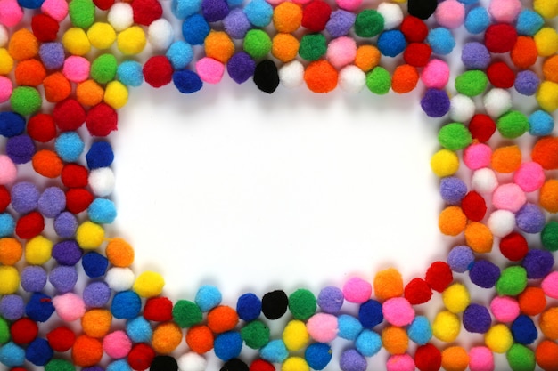 frame of small colored pompons  on white background