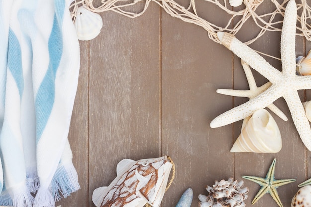 Frame of starfish and sea shells on wooden planks background with copy space