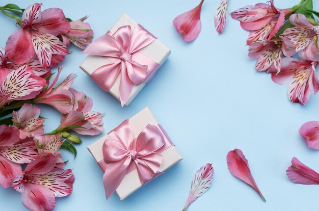 frame for the text of congratulations with flowers of alstroemeria and gift boxes on a blue background greeting card with natural colors background for text with alstromeria flat lay top view