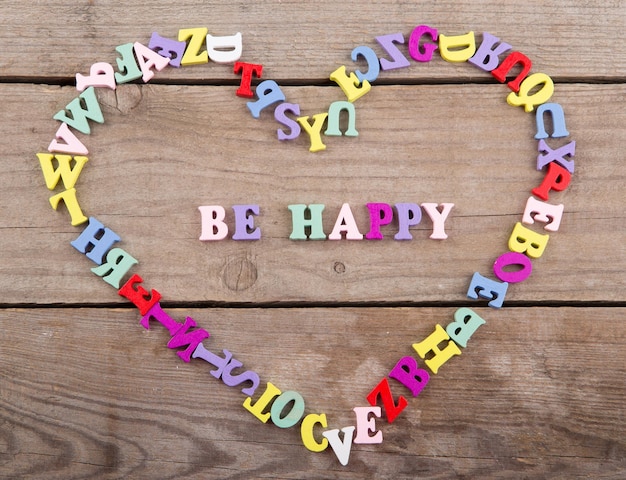 Foto frame van gekleurde houten letters in de vorm van hart en tekst be happy