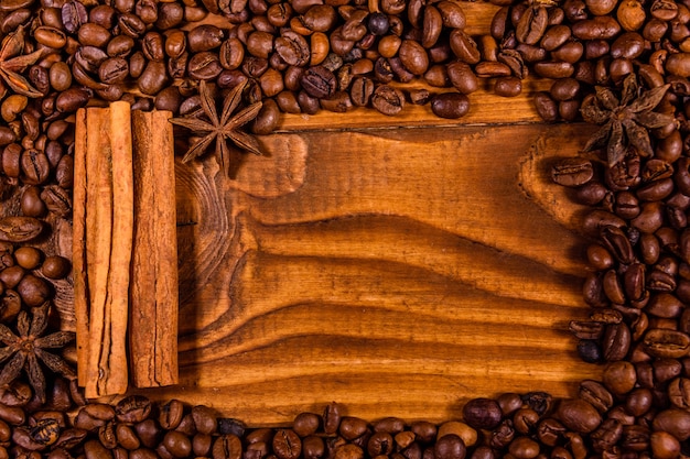 Frame van koffiebonen, steranijs en kaneelstokjes op rustieke houten tafel