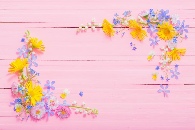 Frame van mooie bloemen op roze houten achtergrond
