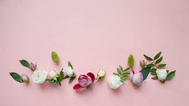 Frame van paarse en roze rozen, witte Lisianthus en verschillende bloemen op roze achtergrond.