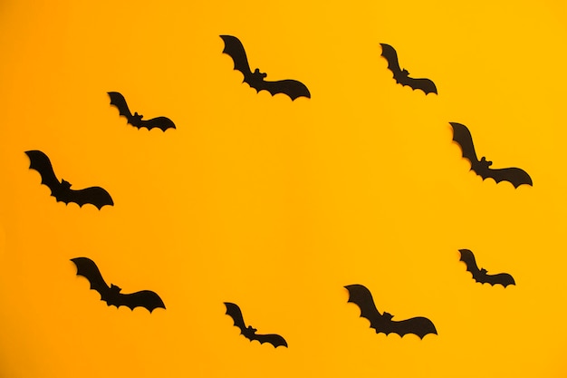 Frame van papieren silhouetten van vleermuizen op een oranje achtergrond. Behandel of bedrieg Halloween