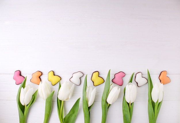 Frame van snoepjes voor pasen vieren. chocolade kleurrijk konijntje en witte tulpen.