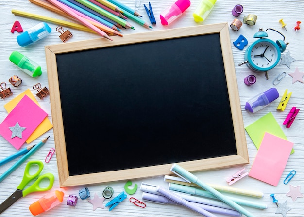 Frame van verschillende briefpapier op witte houten achtergrond, plat lag met ruimte voor tekst. Terug naar school