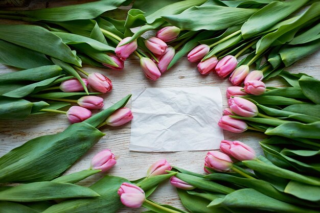 Frame van verse tulpen gerangschikt op houten achtergrond met papier