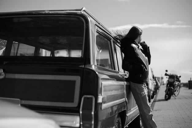 Frame view. Black and white photo outside. Back view of a hipster girl with hair blowing.