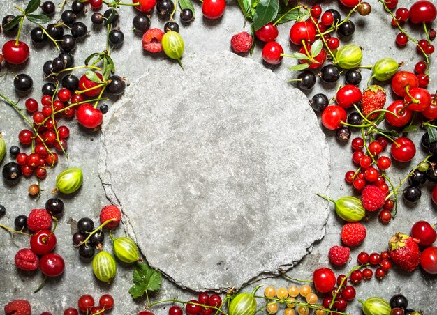 Frame of wild berries with free place for text. On the stone table.