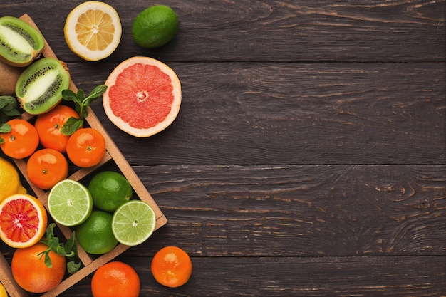 Frame with assortment of citruses on rustic wooden background, copy space. Top view on oranges, lemons, tangerines and other exotic fruits, flat lay