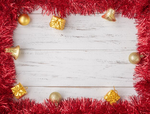 Frame with christmas balls, gift boxes and bells over wooden table with copy space.