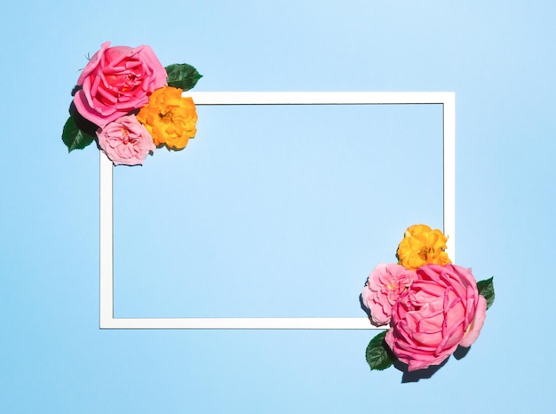 Frame with copy space made of colorful rose flowers and leaves on sky blue background Love concept