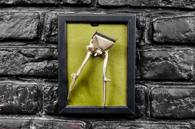 Frame with golden old hair clipper hangs on black brick wall