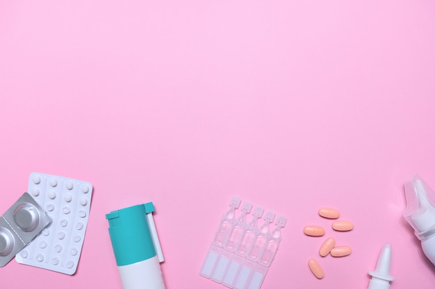 Frame with many pills and tablets on pink background