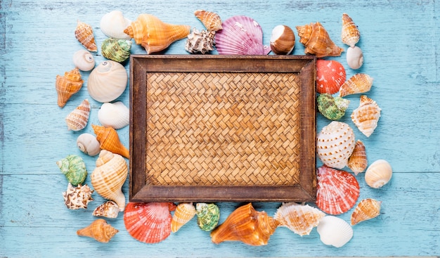 Frame with seashells on blue wooden background