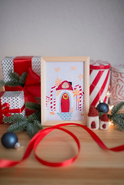 A framed Christmas card stands on a table with gifts