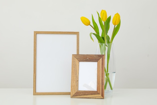 Frames of different sizes on the table near a vase of flowers