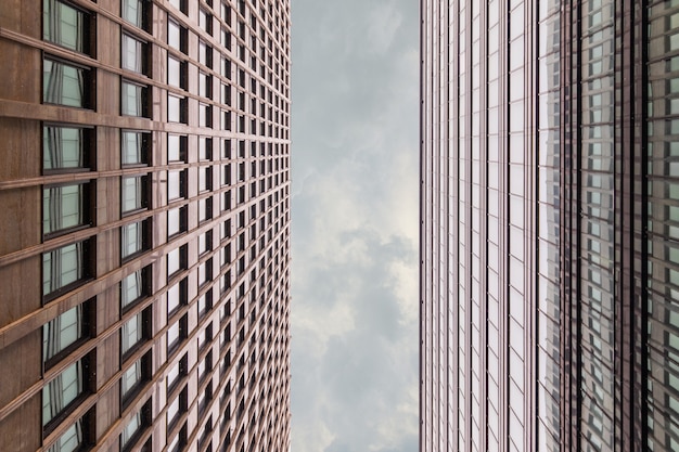 Framing With The Facade Of The Office Building Shot From The Bottom Up With A Vertical Strip Of Gray Sky With Clouds. Business Centre On A Cloudy Day