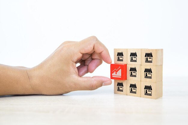 Franchise Hand choose graph icon on cube wooden toy blocks stacked with franchise business store icon for growth and financial marketing planning and bank loan for branch expansion franchisee