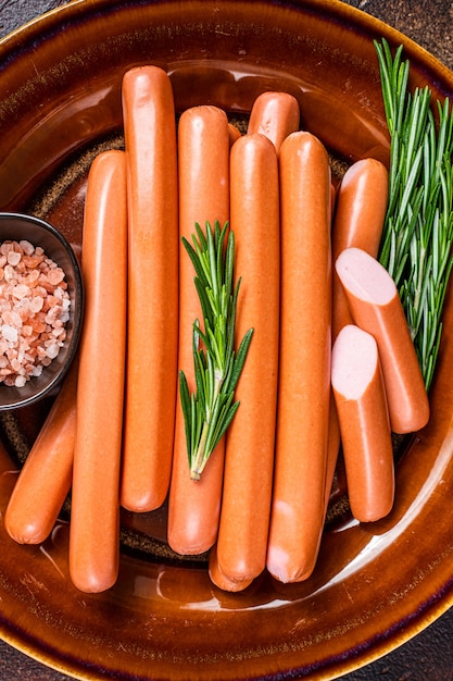 frankfurter raw sausages in a rustic plate with herbs