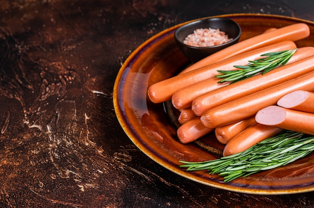 Frankfurter raw sausages in a rustic plate with herbs