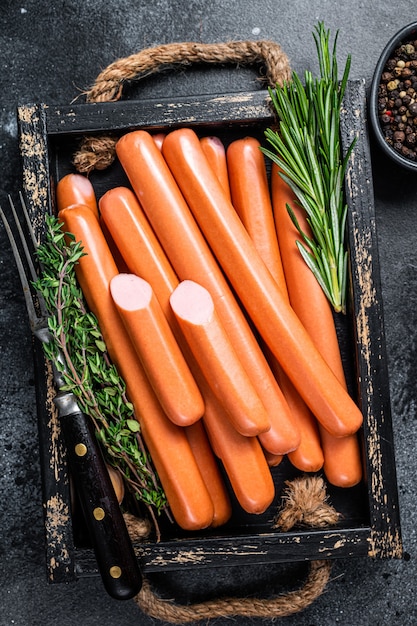 Frankfurter sausages in a wooden tray with herbs