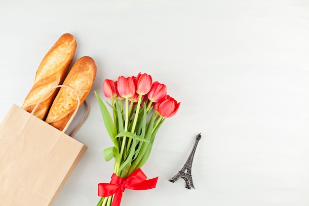 Frans stokbrood in de boodschappentas met de bouquette van rode tulpen