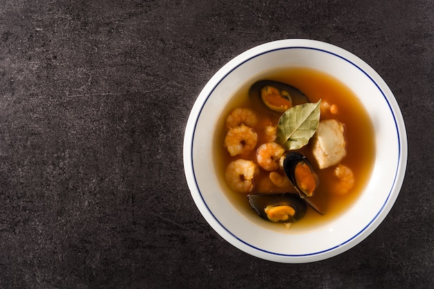 Franse bouillabaisesoep in witte plaat op zwarte achtergrond. Bovenaanzicht kopie ruimte