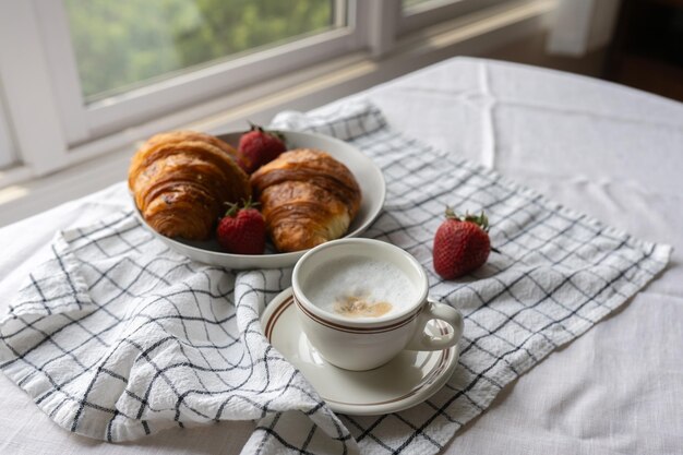 Franse croissants in een geweven mand aangevuld met een kop koffie met melk Een heerlijk ontbijt