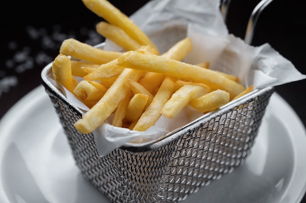 Franse frietjes in een metalen raster, op een witte plaat
