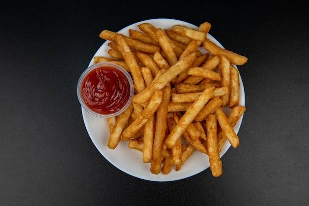 Franse frietjes met ketchup op donkere achtergrond bovenaanzicht