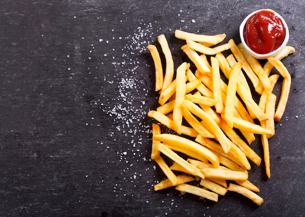 Franse frietjes met ketchup op donkere tafel, bovenaanzicht