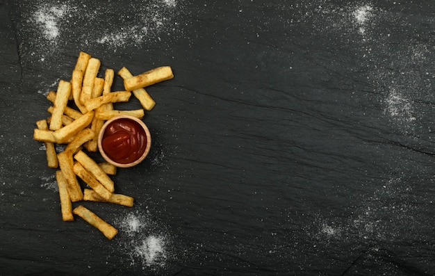 Franse frietjes met ketchup op donkere tafel