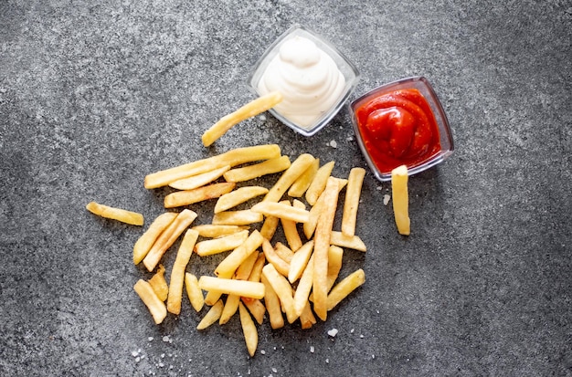 Franse frietjes met verschillende sauzen op een stenen ondergrond