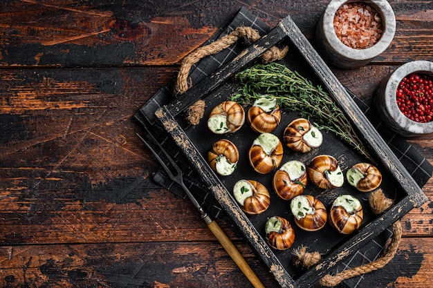 Franse gastronomische Escargots Slakken met kruidenboter in een houten dienblad Houten achtergrond Bovenaanzicht Kopieer ruimte