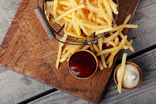 Franse gebraden aardappels in metaalmand op houten achtergrond