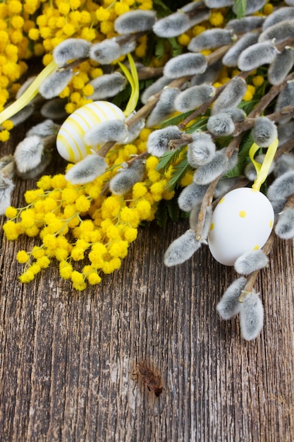 Franse gele mimosa en katjes met paaseieren op houten tafel